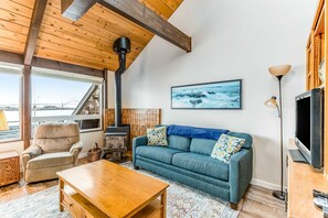 A cozy living room with a sofa, armchair, wooden coffee table, and a fireplace. - Private Bayfront Home with Fishing Dock - Dogs Welcome (Newport)