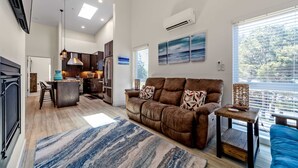 Ein modernes Wohnzimmer mit einer braunen Couch, einem blauen Sofa und einer Küche im Hintergrund.