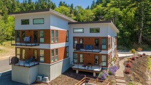 Ein modernes, zweistöckiges Haus mit Balkonen, großen Fenstern und einem angelegten Garten.