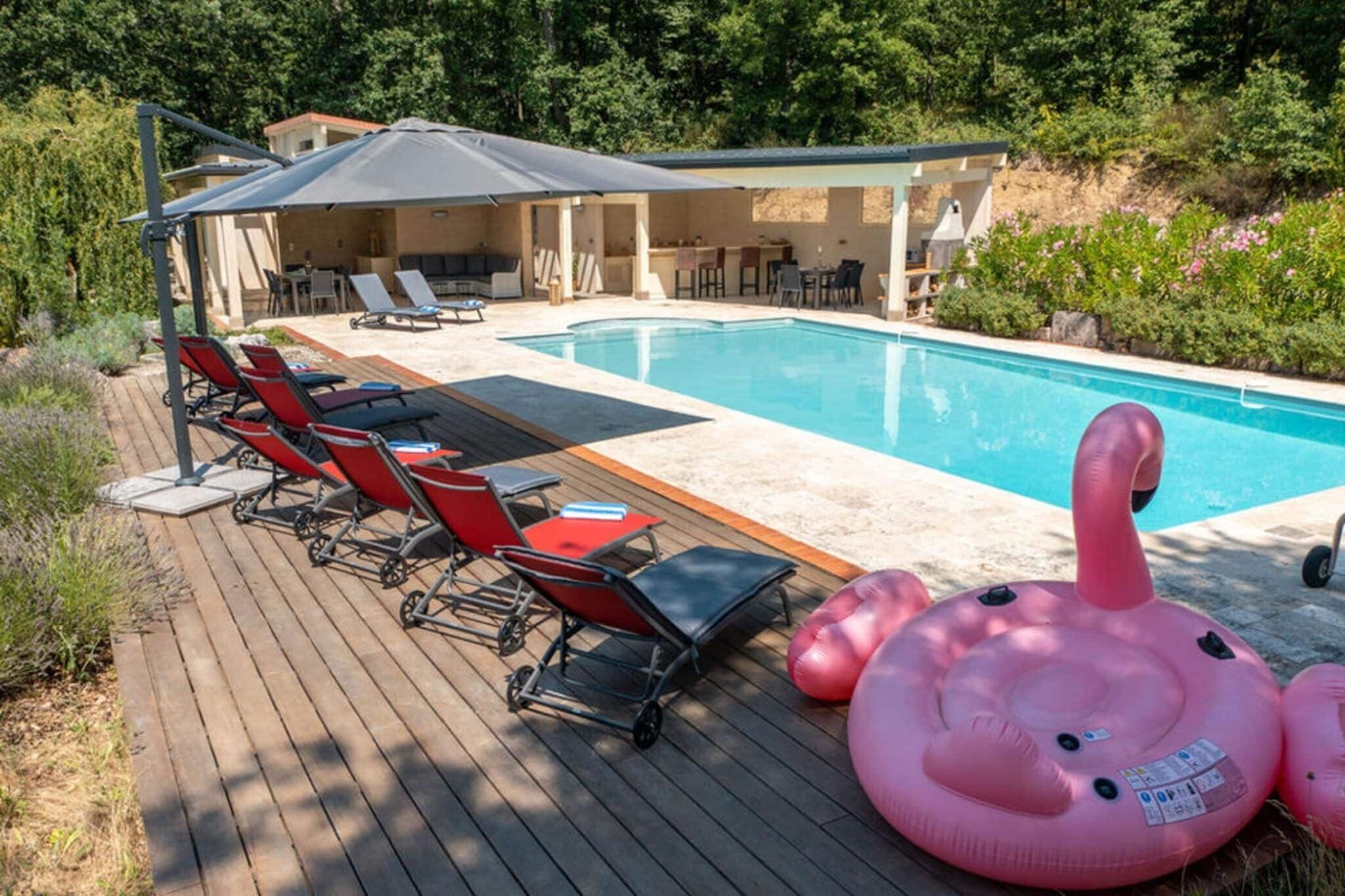 Un espace piscine avec des chaises longues, un coin salon abrité et des jeux gonflables.