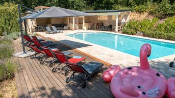 A pool area with lounge chairs, a covered seating area, and inflatable toys.
