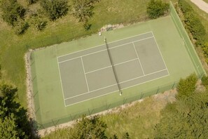 Eine Tennisanlage aus der Vogelperspektive, umgeben von viel Grün.
