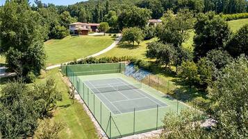 A tennis court surrounded by greenery and houses.