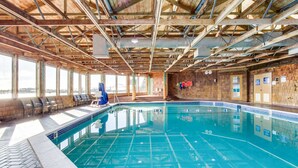 An indoor swimming pool with a wooden ceiling, clear glass walls, and a tiled floor. - Waterfront Condo with Private Deck, Bay Views, Pool, Hot Tub, & Sauna (Newport)