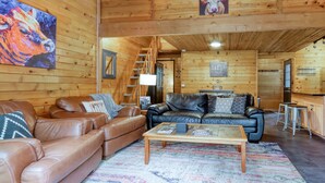 Ein Holzinterieur mit Ledersofas, einem Couchtisch und einem Gemälde von einer Kuh.