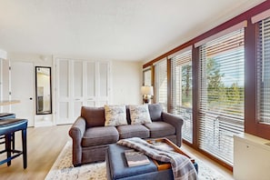 A living room with a sofa, a coffee table, and a dining area with a bar stool. - Cozy condo with shared pool, hot tub, sauna, fitness room, washer and dryer (Bend)