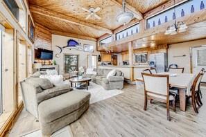 A spacious living area with a large sofa, a dining table with chairs, a kitchen area, and a ceiling fan. - Incredible dog-friendly home with pool table, fast WiFi, gas fireplace, and W&D (Ocean Park)
