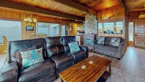 A cozy living room with leather sofas, a wooden coffee table, and a fireplace. - Oceanfront, Dog-Friendly Home with Fireplace, Ocean View, Beach Access & WiFi (Yachats)