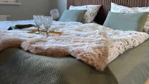Un lit bien fait, avec une couverture moelleuse, deux oreillers et deux verres en verre transparent posés sur un plateau.