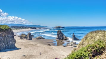 Une plage côtière bordée de formations rocheuses, sous un ciel dégagé.