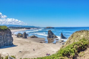 Une plage côtière bordée de formations rocheuses, sous un ciel dégagé.