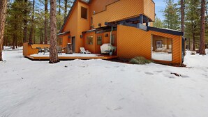 A modern wooden cabin with a deck, surrounded by snow and trees. - Rustic-chic home with patio, pools, hot tubs, & fitness center (Black Butte Ranch)
