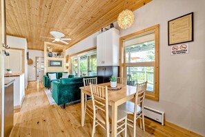 A wooden ceiling, a dining table with chairs, a green sofa, and a kitchen area. - Charming coastal home with water views, large covered deck (Gold Beach)