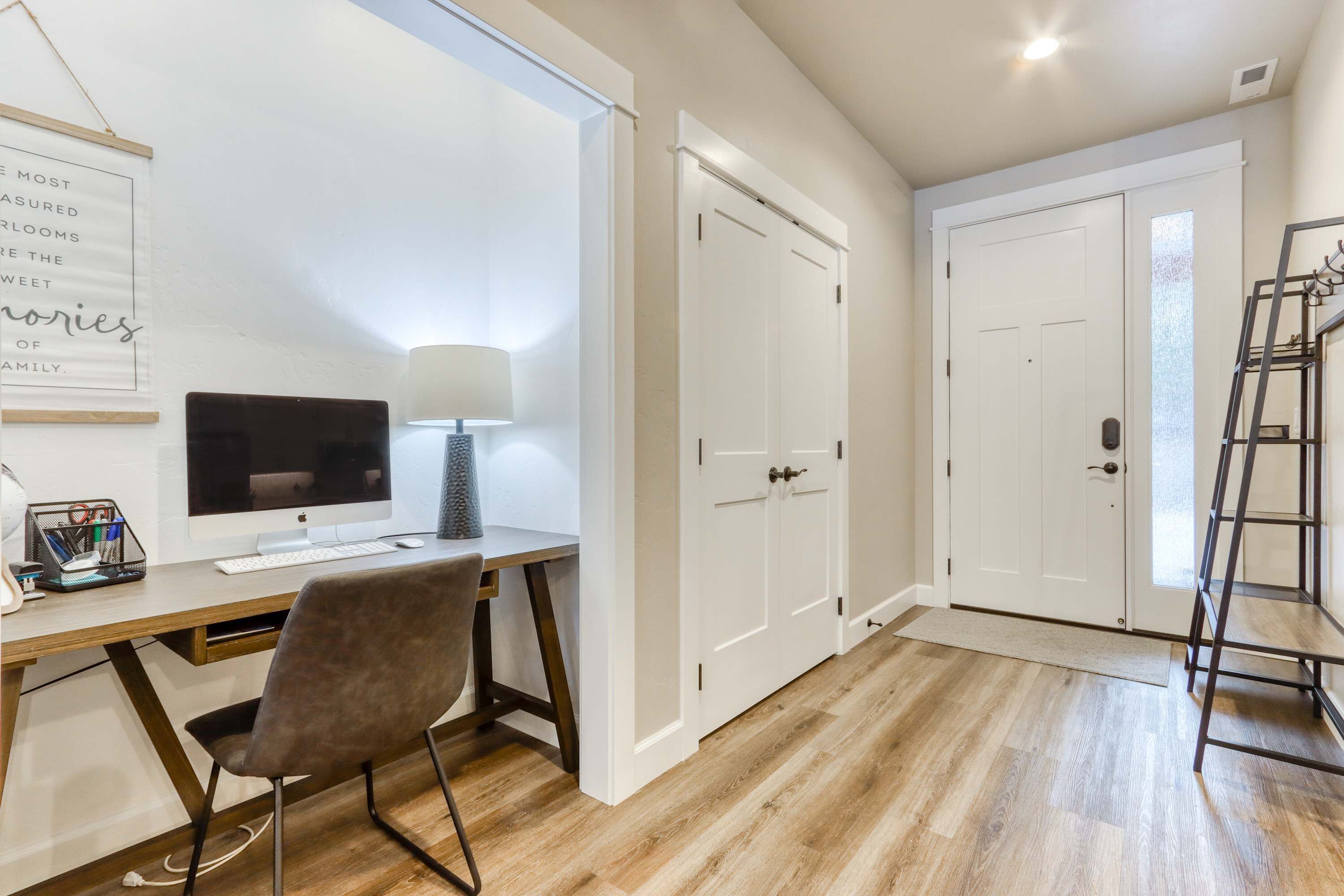 A room with a desk, computer, chair, white doors, and a ladder.