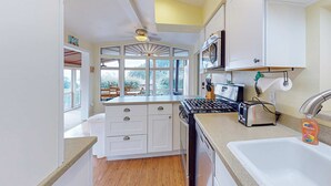 A kitchen with a stove, sink, and cabinets. - Oceanfront home with private hot tub, walls of glass & spectacular view (Brookings)