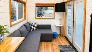 Un interior moderno con un sofá modular, un televisor de pantalla plana y un techo de madera.