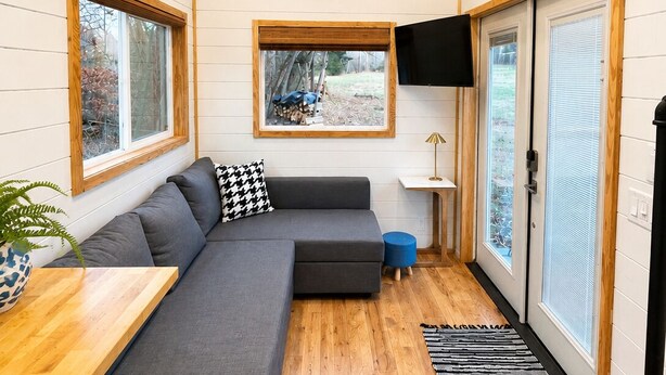 Un intérieur moderne avec un canapé d’angle, un téléviseur à écran plat et un plafond en bois.