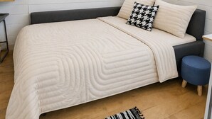 Un dormitorio con cama, ventana, mesita de noche y una silla.