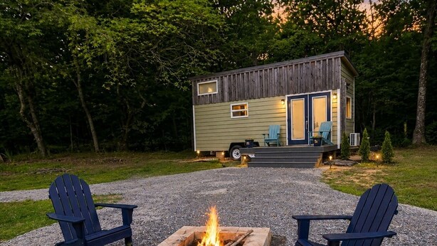 Una cabaña pequeña con un brasero y dos sillas Adirondack en el frente.