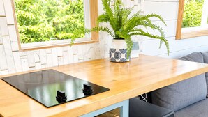 Une cuisine compacte dotée d’un plan de travail en bois, d’un évier encastré et d’une fenêtre donnant sur un espace verdoyant.