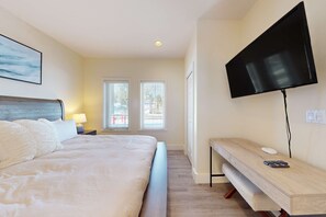 Hotellihuone, jossa on sänky, televisio, työpöytä ja kaksi ikkunaa.