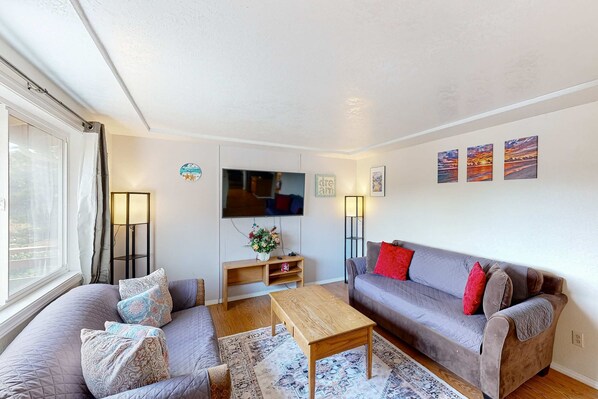 A living room with a sofa, a coffee table, a TV, and artwork on the wall.