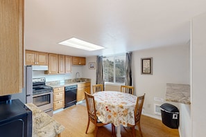 A kitchen with wooden cabinets, a stove, and a dining table with chairs.