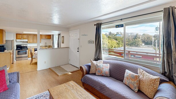 A modern living room with a sofa, a coffee table, and a view of the outside. - Dog-friendly duplex in the Heart of Nye beach near the beach & downtown (Newport)