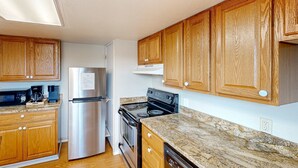 A kitchen with wooden cabinets, stainless steel appliances, and granite countertops. - Dog-friendly duplex in the Heart of Nye beach near the beach & downtown (Newport)