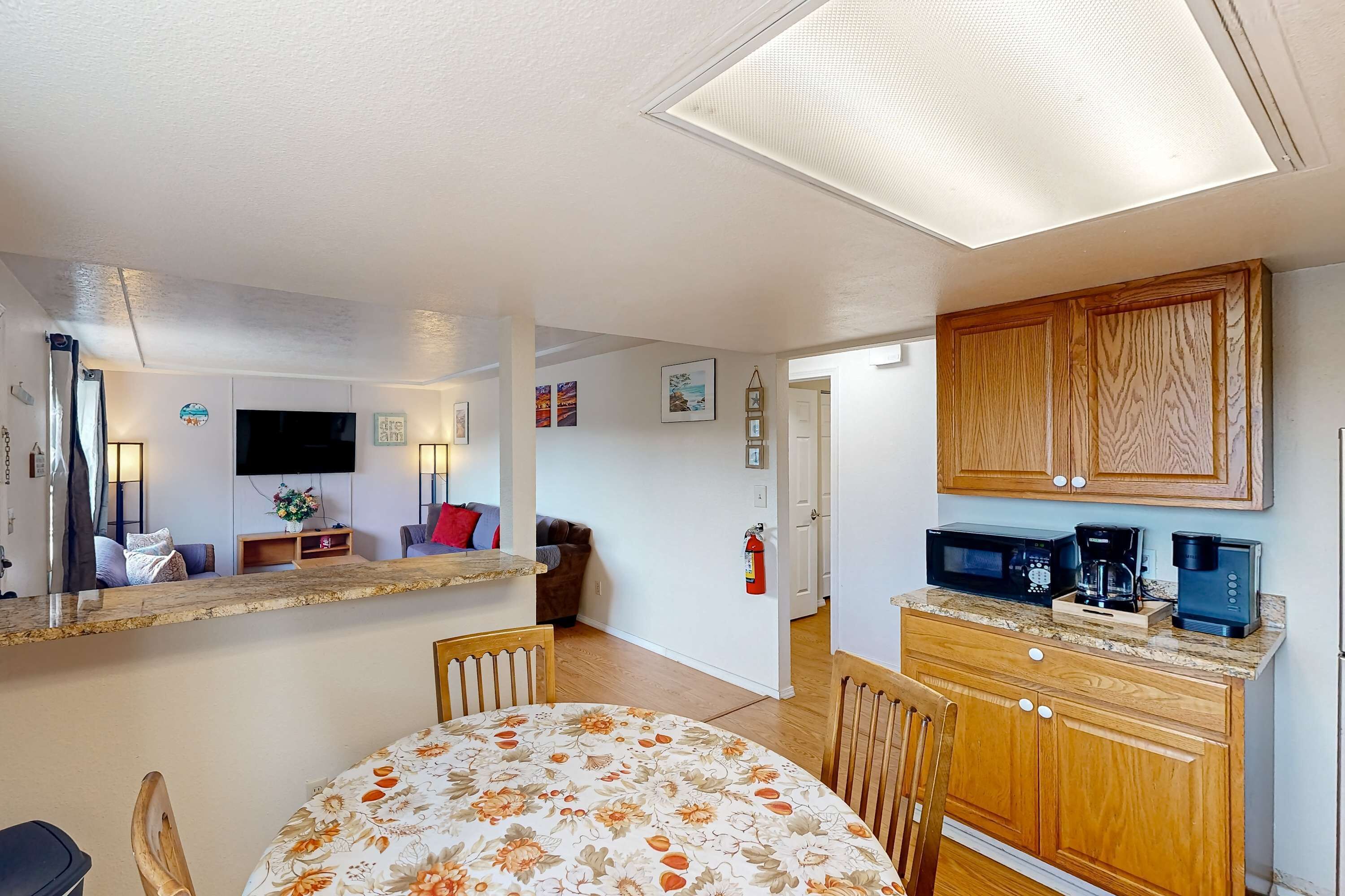 A modern kitchen with wooden cabinets, a microwave, and a coffee maker.