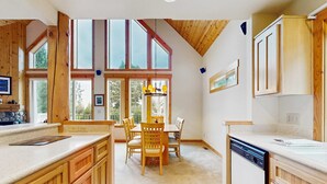 A kitchen with wooden cabinets, a dining table with chairs, and large windows. - Inviting chalet with grill, patio & access to pools, hot tub, golf, tennis & gym (Redmond)