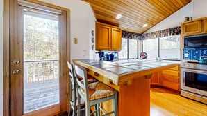 Cucina con mobili in legno, un'isola grande con sgabelli da bar, un frigorifero e un forno a microonde.