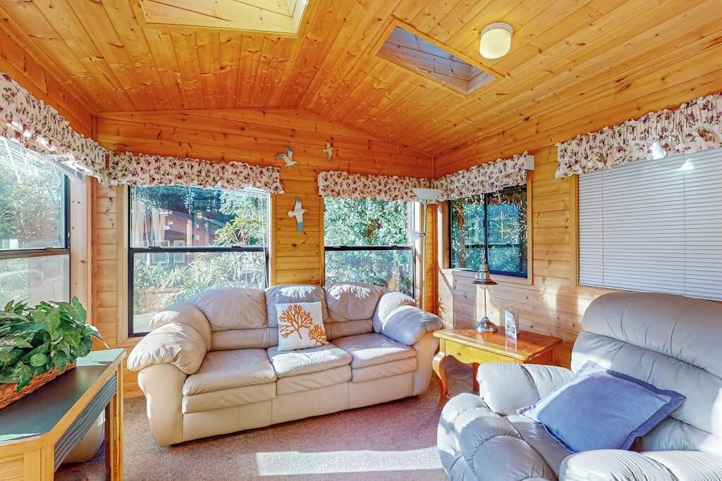 A cozy room with a wooden ceiling, a sofa, a chair, and a small table.