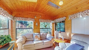 A cozy room with a wooden ceiling, a sofa, a chair, and a small table.