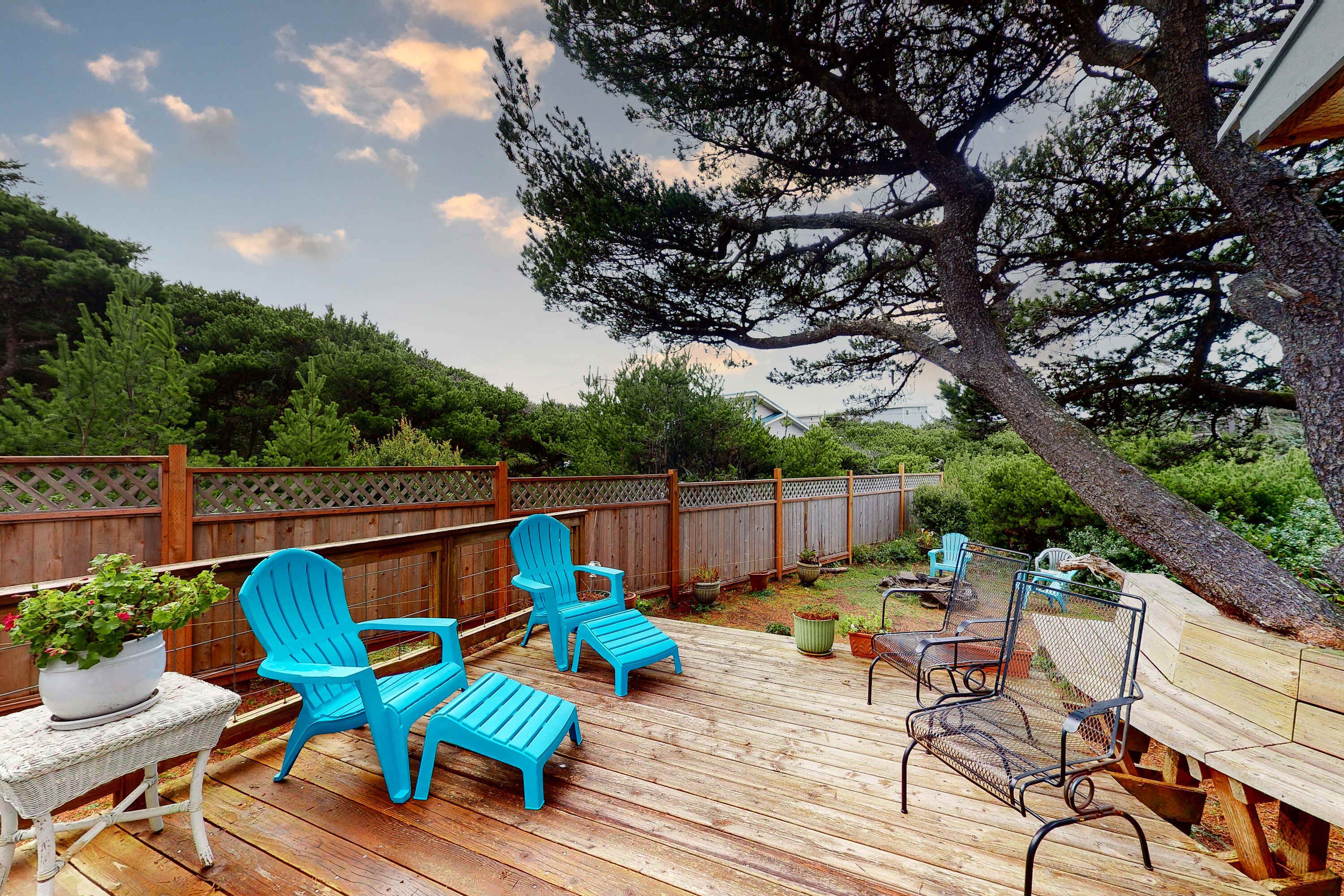 Une terrasse en bois avec des chaises Adirondack bleues, une table en osier et un banc en métal.