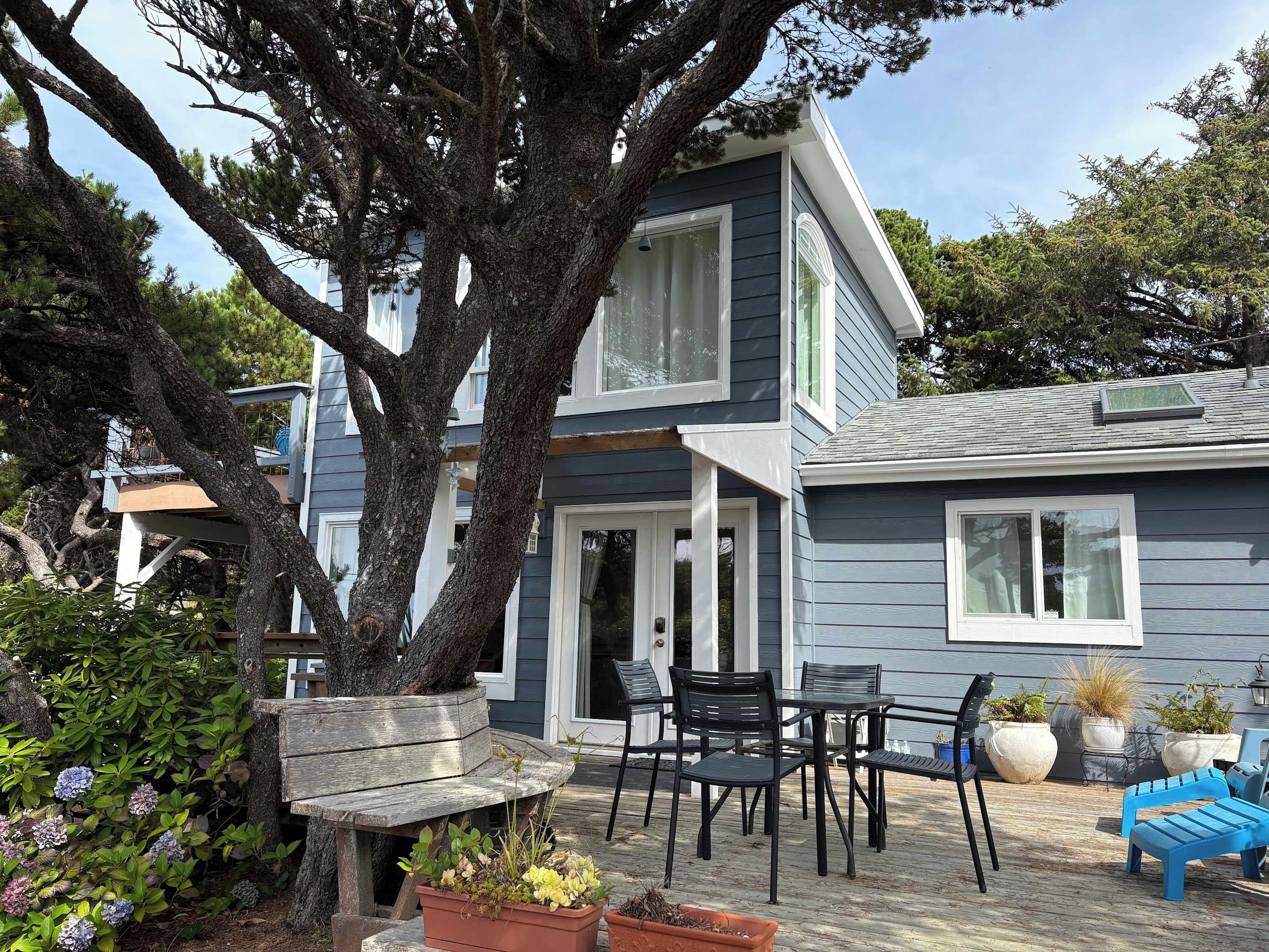 A two-story house with a patio area featuring outdoor furniture and potted plants.