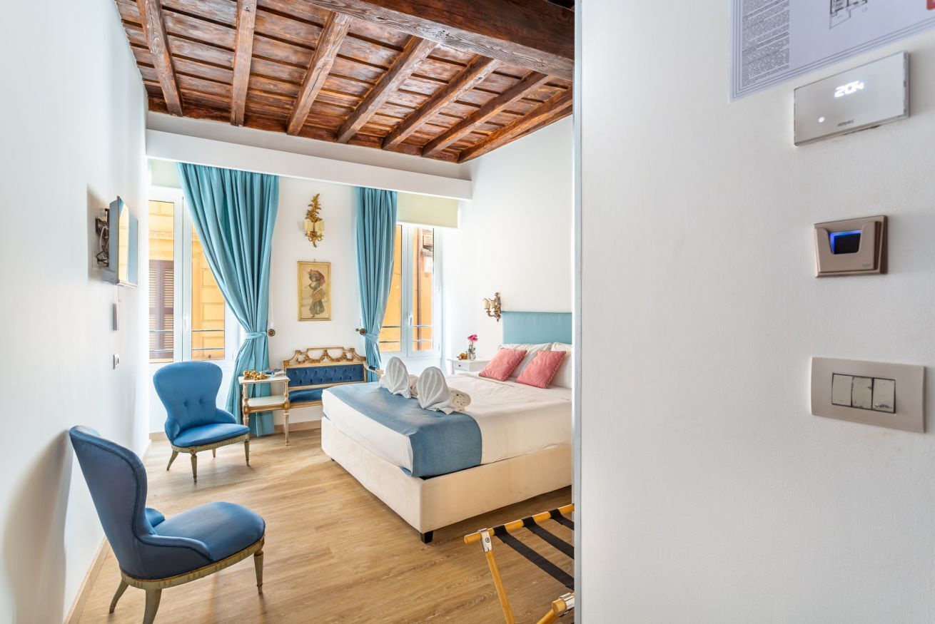 Ein Schlafzimmer mit einem Bett, einem Sessel, einem Tisch und einem Fenster mit Vorhängen.