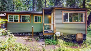 Una cabaña con base de piedra, fachada de madera y ventanas grandes.