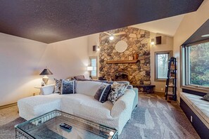 A cozy living room with a stone fireplace, a sofa, and a coffee table.