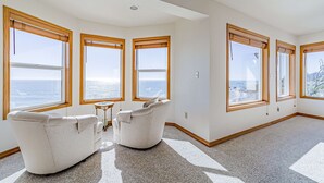 A spacious room with large windows, a white sofa, and a small table. - Gorgeous oceanfront estate with amazing views & hot tub - steps to quiet beach (Brookings)