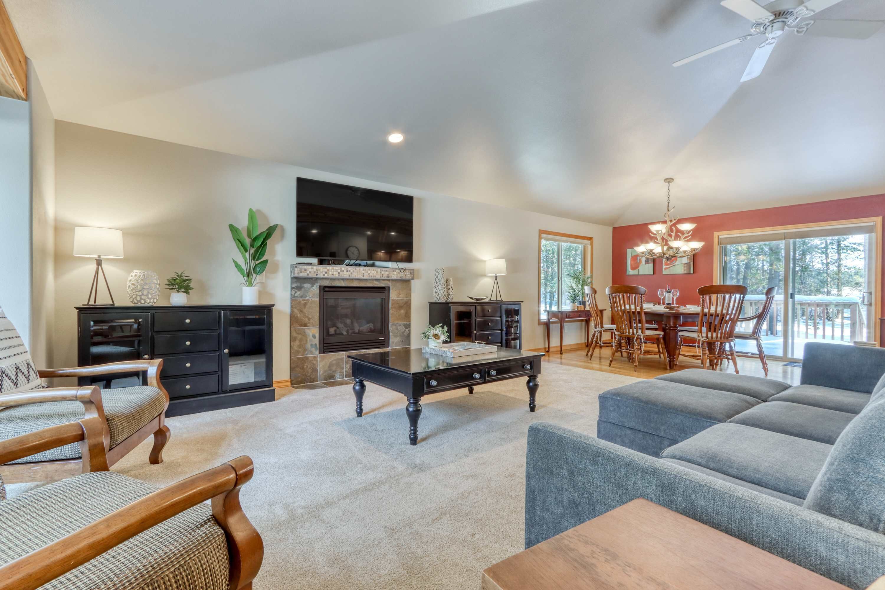 A living room with a fireplace, a dining area, and a large window.