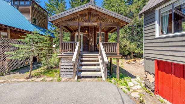 Una cabaña rústica con un porche de madera, una escalera que lleva a la entrada y un letrero que dice 'GRETEL'.