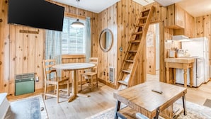 Un interior de madera con comedor, cocina y televisor montado en la pared.