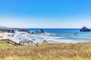 A coastal beach with rocky outcrops, a wooden pier, and a gazebo. - Dog-friendly cottage on the bluff with unobstructed ocean views (Bandon)