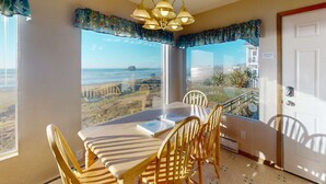 A dining area with a view of the ocean, a chandelier, and a door with a sign.
