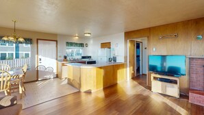 A kitchen with a refrigerator, microwave, and a television on a stand.