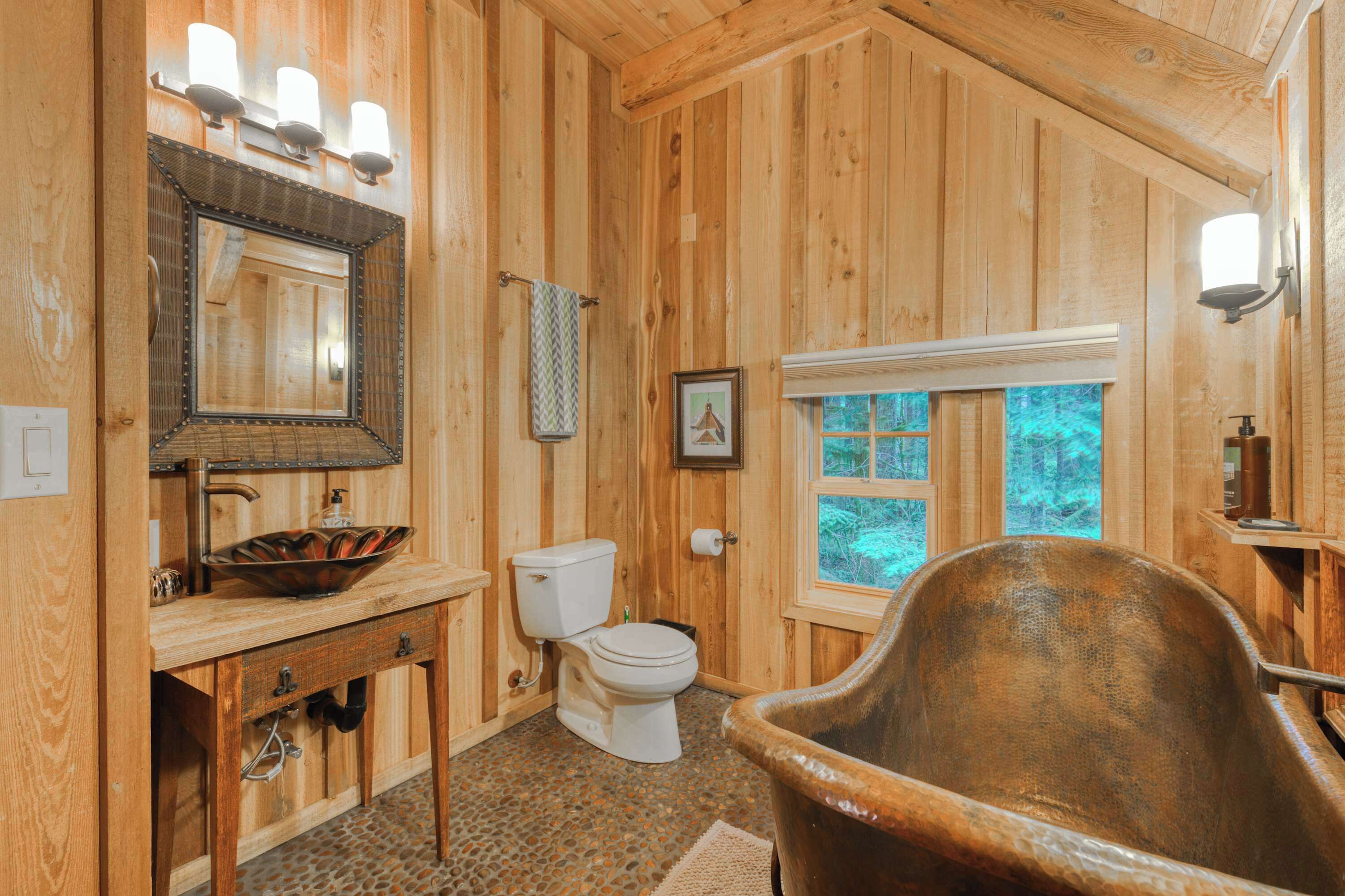 A wooden bathroom with a sink, toilet, and a bathtub.