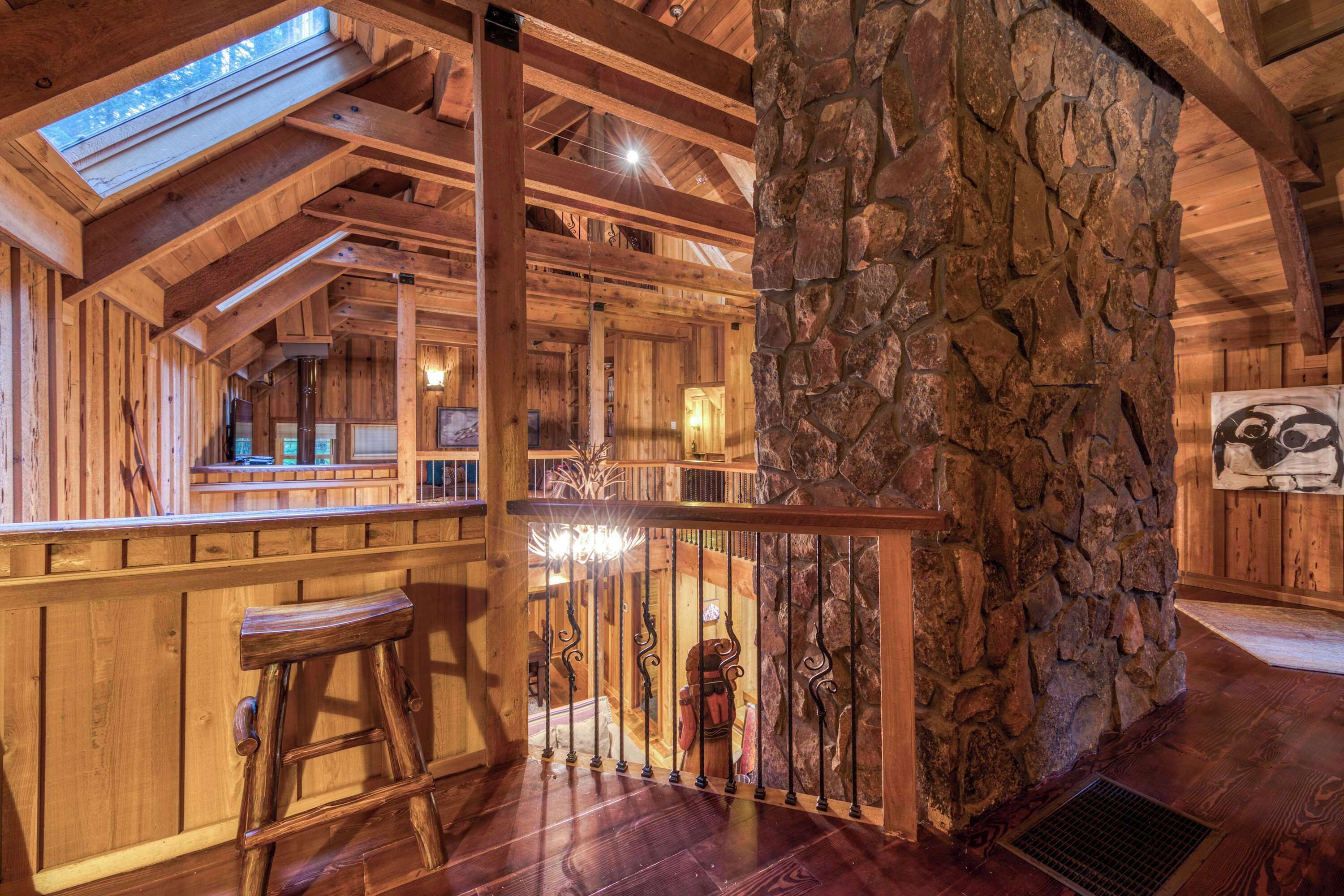 Un intérieur en bois avec un mur en pierre, des poutres apparentes, un escalier et un coin bar.