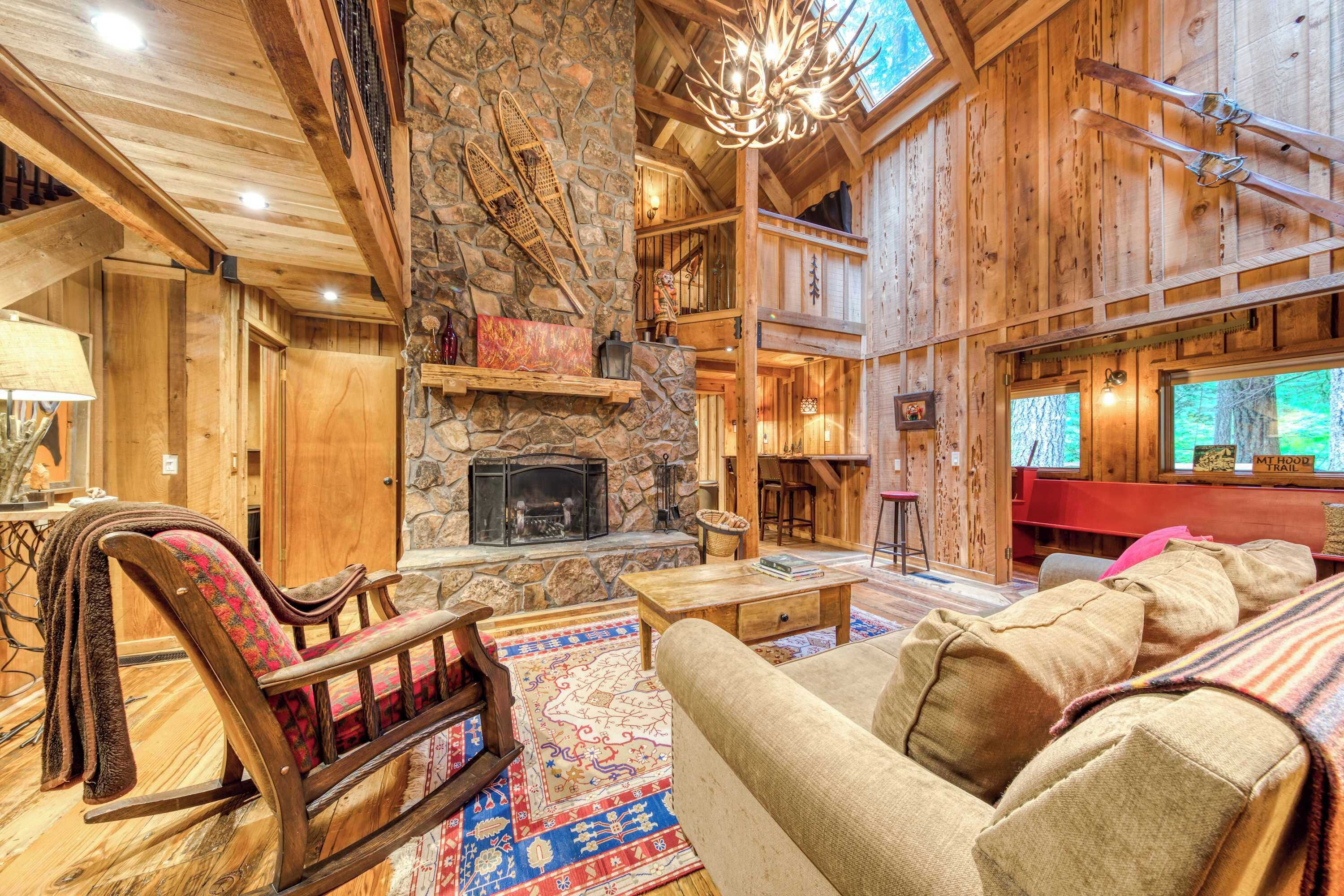 A rustic interior with a stone fireplace, wooden beams, a rocking chair, and a sofa.
