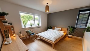 Un dormitorio con cama, escritorio y plantas en macetas.